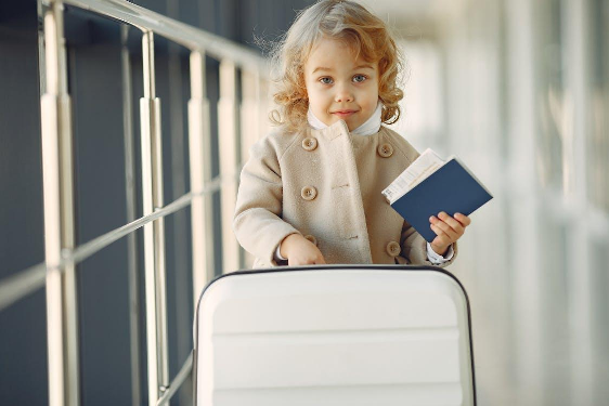A cute little girl holding a suitcase and passport, ready for her trip abroad.