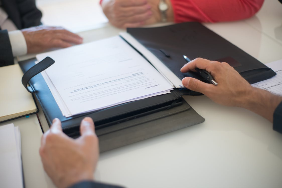 A man with hands on a table, presenting contract papers, representing the legal and administrative steps involved in obtaining dual citizenship.