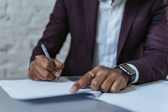 A man writing on white paper with a black pen, symbolizing the application process for dual citizenship and associated documents like US passports.