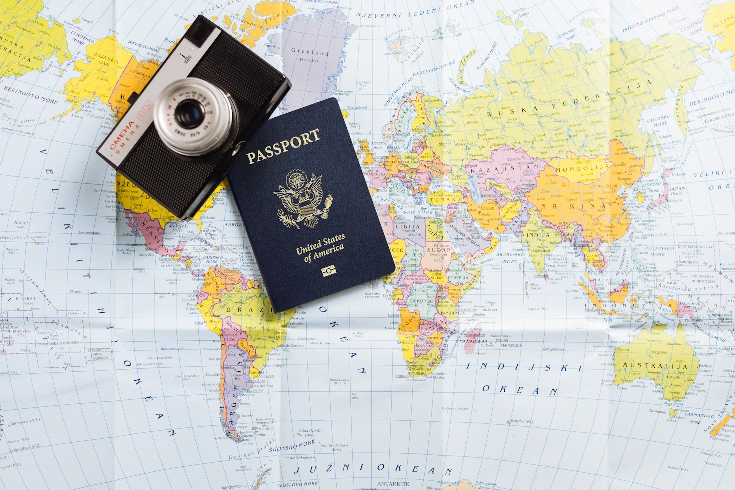A passport on top of a map next to a camera